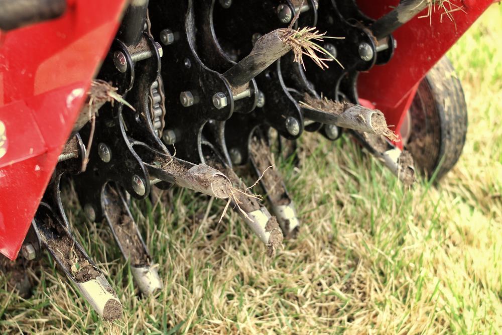 Close-up view of a red aerator performing aeration on a lawn